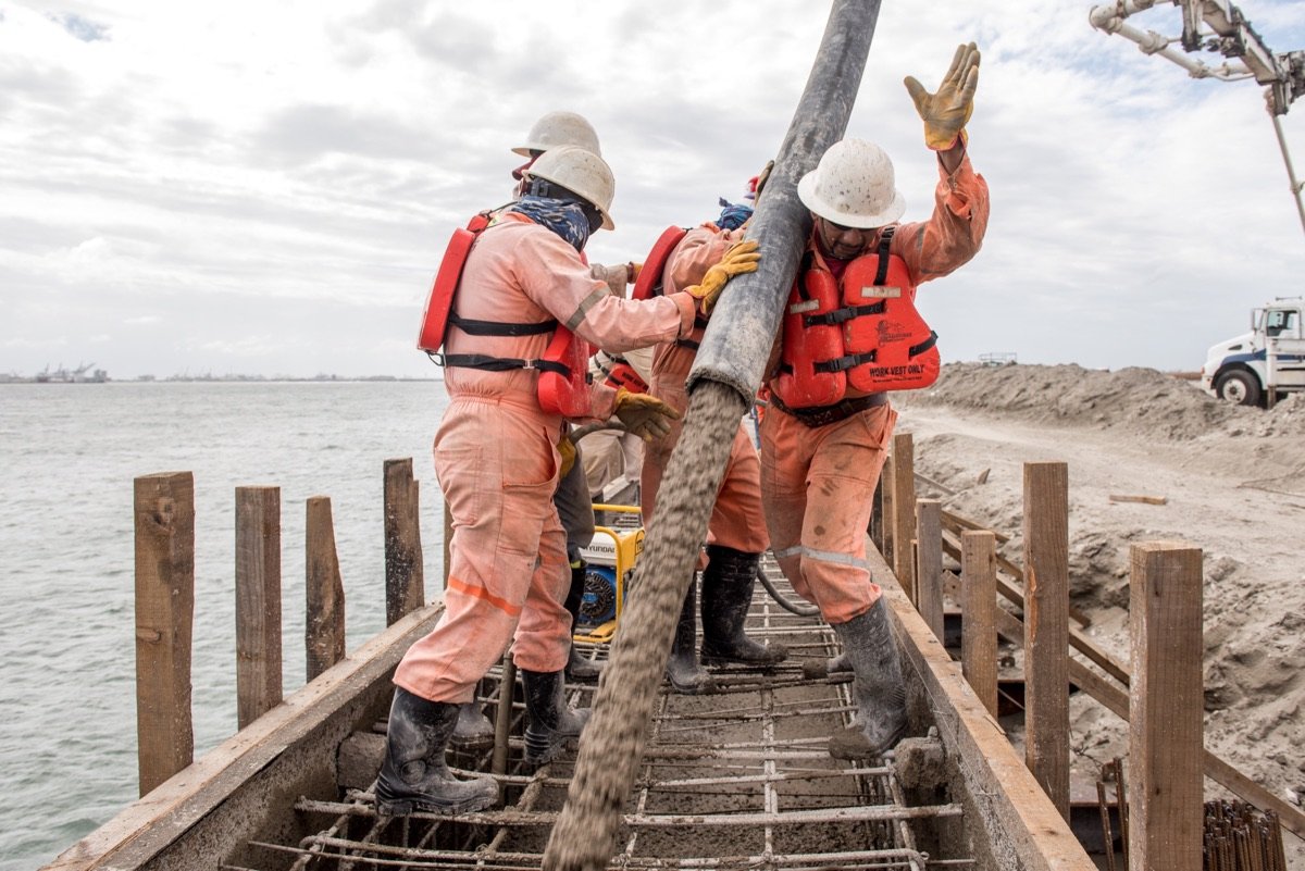 Trabajadores colocando pilotes frente al mar